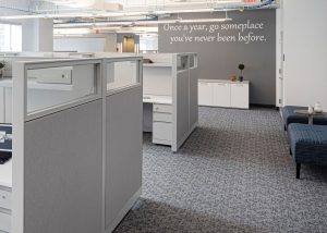 Corporate interior design with workstations and wall quote: Once a year go someplace you've never been before